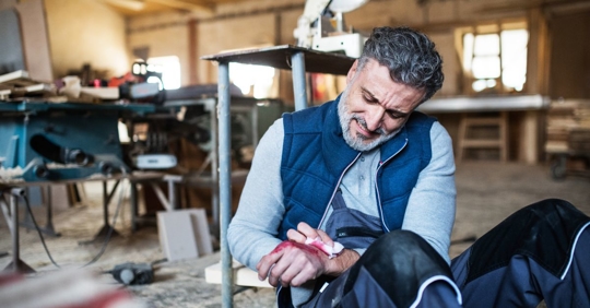man grabbing injured hand at work